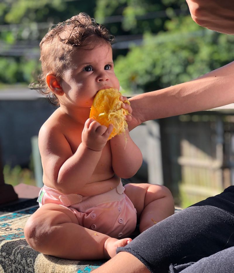 Imagem de um bebê se alimentando ao ar livre