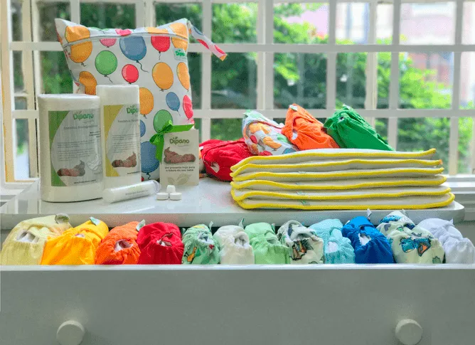 KIt de fraldas de pano em cima de um armãrio branco e com a gaveta aberta.