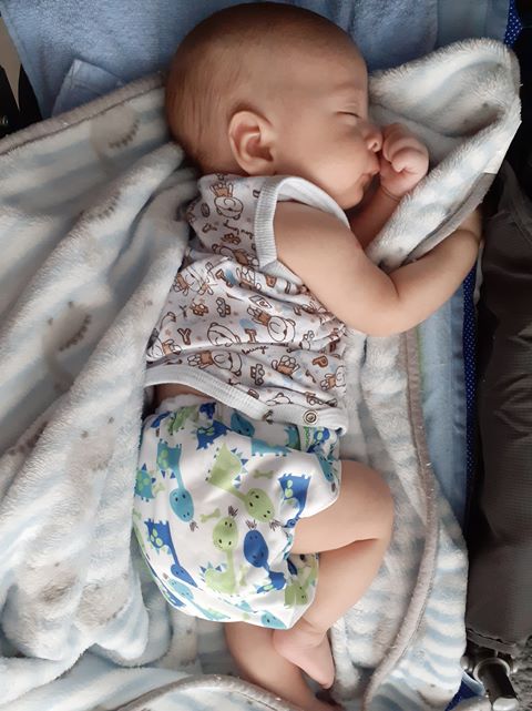 Bebê com fralda estampada dormindo de lado.
