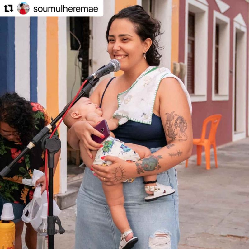 Mãe cantando no microfone segurando bebê no colo