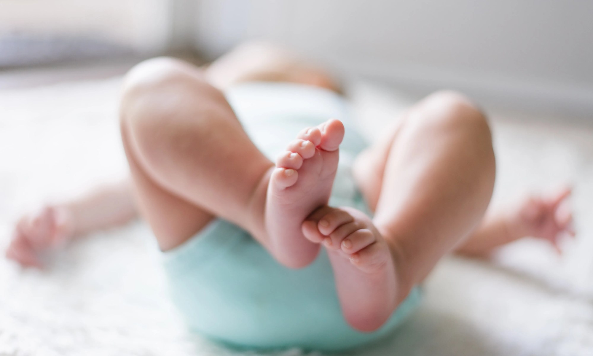 bebê deitado com os pés juntos