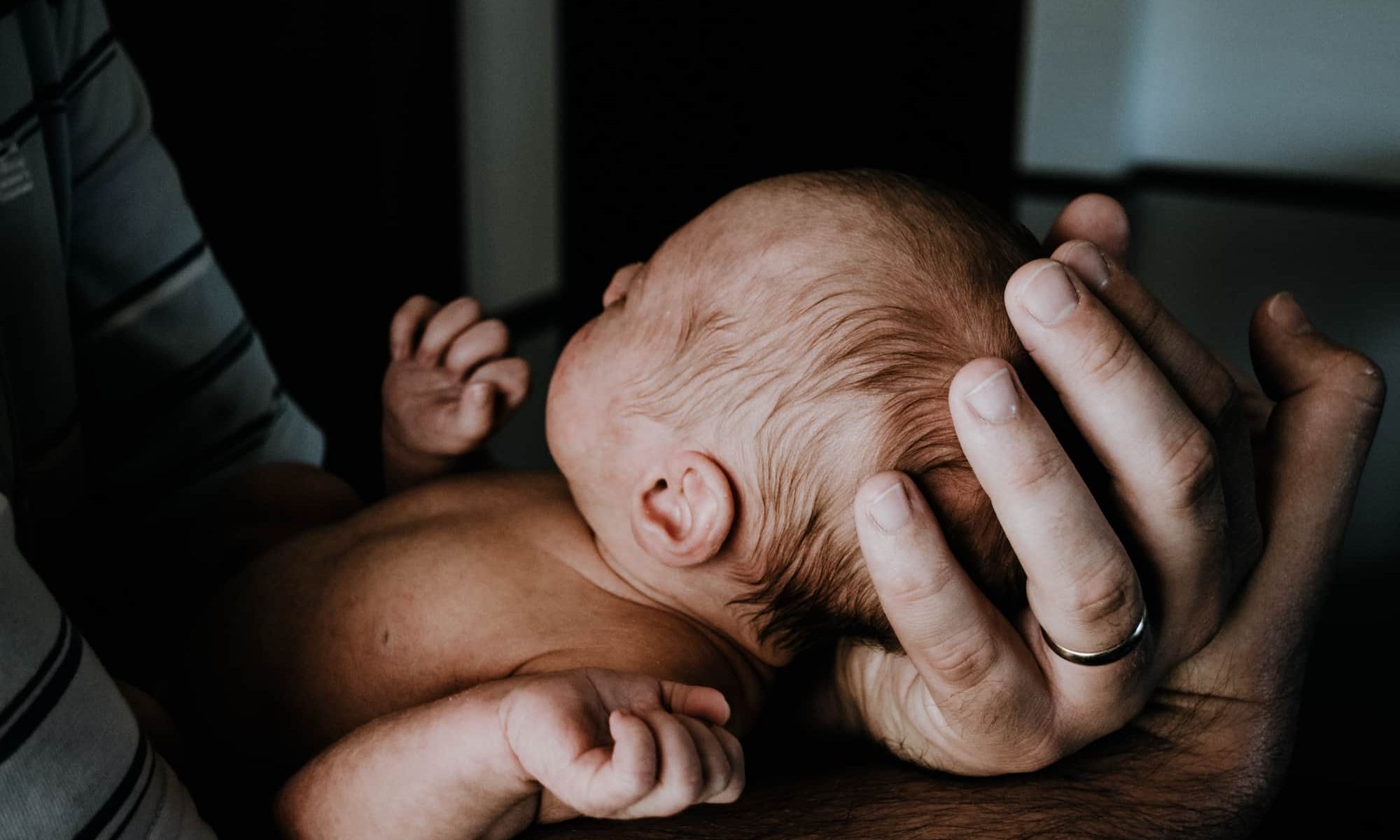 Bebê recém nascido nos braços do pai.