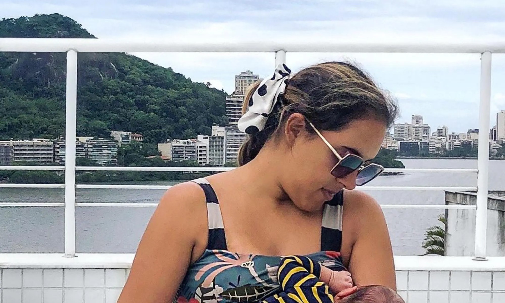 Mãe na piscina amamentando um bebê