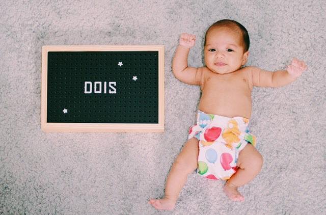 Bebe ao lado de quadro com número dois