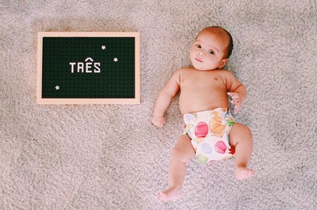 Bebe ao lado de quadro com número três