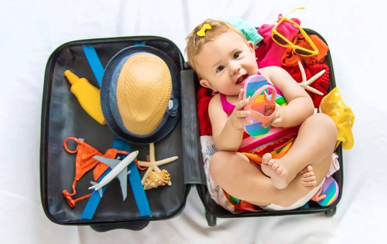 Bebê deitado dentro de uma mala de viagem.