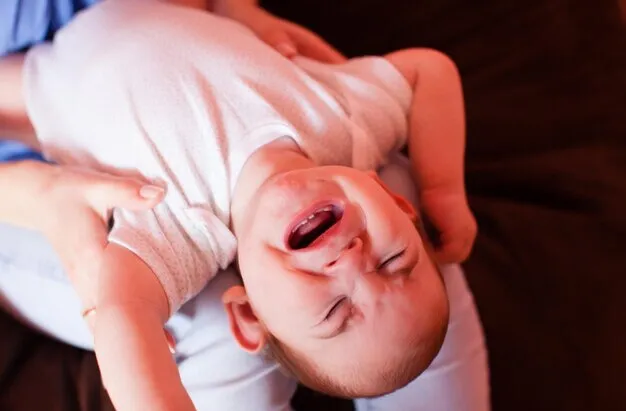 Bebê chorando no colo.