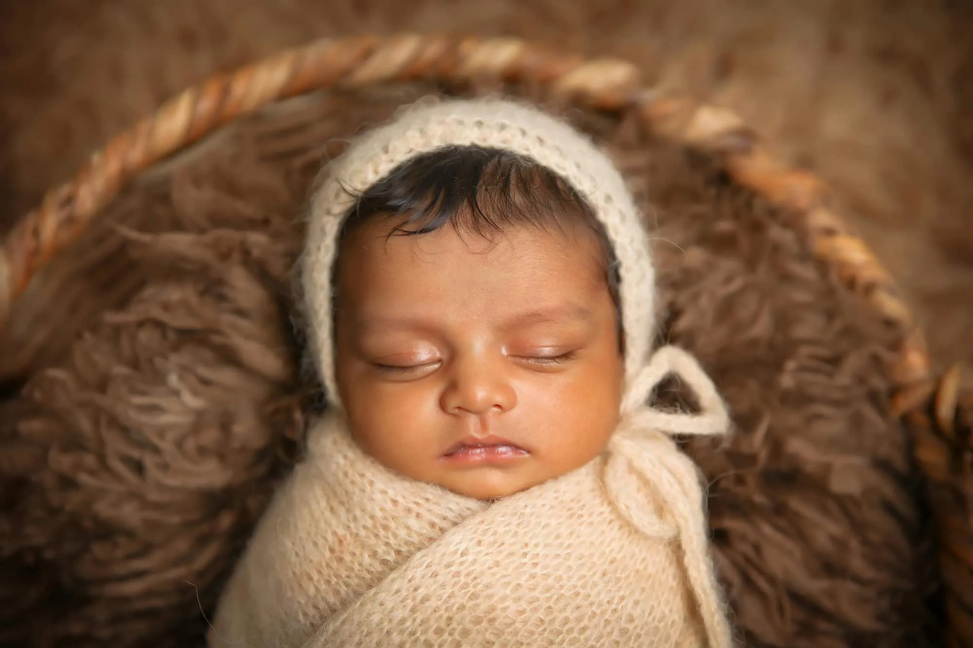 Bebê dormindo enrolado em uma manta e com uma touca de lã.