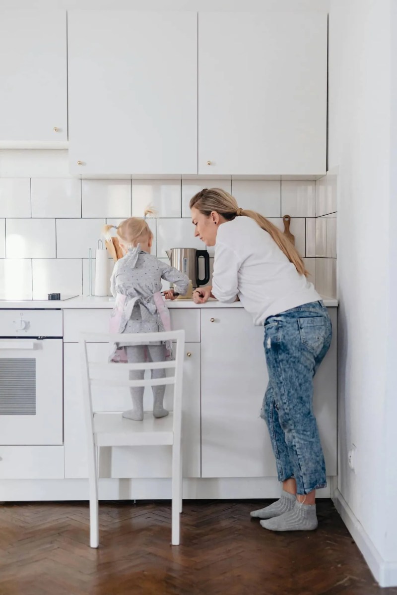 Mãe observando sua filha no balção da cozinha.