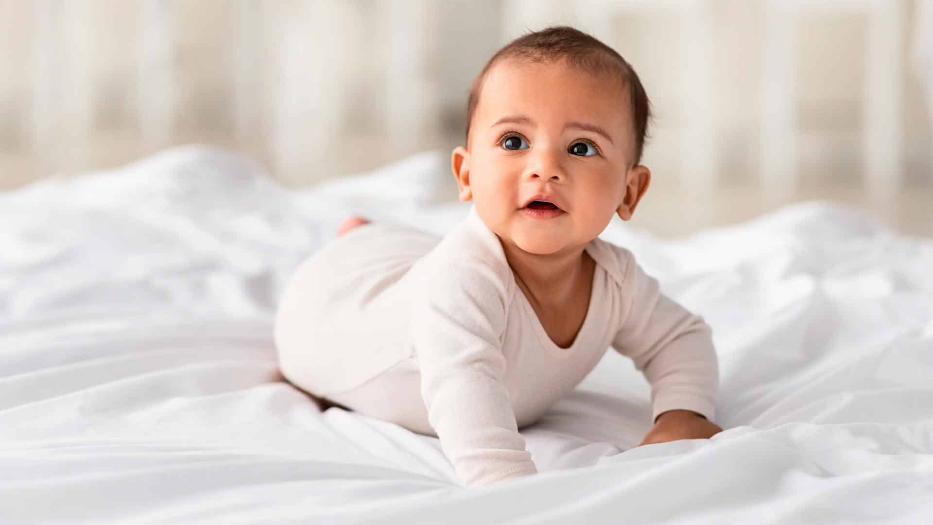 Bebê deitado em uma cama com lençóis brancos, transmitindo uma sensação de tranquilidade e conforto.
